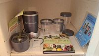 Overall view of NutriBullet Magic Bullet juicer/blender with accessories, cups, Green Drink Diet book, and instruction materials.