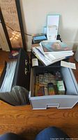 Overall view of storage drawer filled with paint box, watercolor markers, brush top pens, photo paper, business cards, notebooks and other office items on top