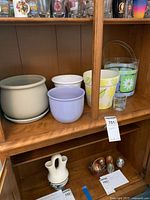 Four planters and a metal ice bucket placed on a wooden shelf with cups in the background