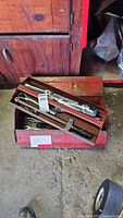 Overview photo of red metal toolbox with various hand tools including ratchets, breaker bars, and torque wrench handles visible inside.