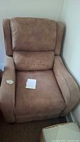Front view of brown felt-like recliner chair showing seat, backrest and armrests. Shows wear and discoloration.