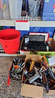 Shelf display with boxes and bucket containing socket sets and assorted hand tools for automotive or mechanical use