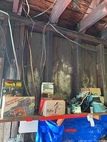 Photo of wooden shelf with full view of soldering equipment including torch kit, electric engraver and pressure tester boxes with other tools