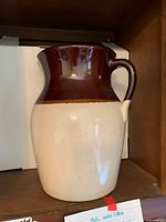 Front view of stoneware water pitcher showing brown glazed top and cream textured body