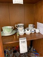 Whole shelf with teacups, saucers, hen figurines, and miniatures