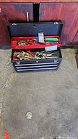 Black Craftsman metal toolbox with 3 drawers open, showing a variety of hand tools inside compartments and trays