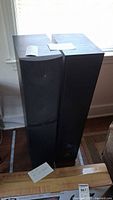 Pair of tall black Infinity RS5 tower speakers side by side showing front and top surfaces with front grill on one speaker