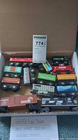Wooden magnetic trains set in a cardboard box showing most of the cars and cabooses with clear visibility of labels and colors.