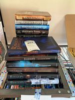 Stack of Artemis Fowl and Ranger's Apprentice hardback books visible on metal shelf