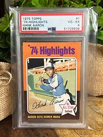 Front view of 1975 Topps '74 Highlights Hank Aaron baseball card in PSA holder showing front design with player image and text.