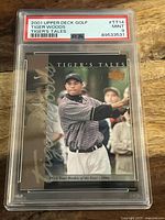 Front view of 2001 Upper Deck Tiger Woods Rookie Card graded PSA 9 Mint in protective case showing Tiger Woods mid-swing with signature.