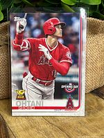 Front view of Shohei Ohtani baseball card showing him in Angels red uniform with Topps logo and Rookie Cup trophy.