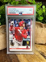 Front view of PSA graded Shohei Ohtani card in slab showing player swinging bat in red LA Angels uniform with PSA MINT 9 label.