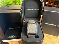 Watch displayed in original black Emporio Armani box with instructions booklet visible.