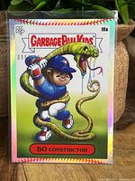 Front view of Garbage Pail Kids Bo Constrictor card with Bo Bichette baseball player character and snake illustration, showing holographic refractor surface and serial number.