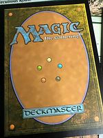 Back of a Magic: The Gathering card showing Deckmaster logo and colored mana symbols