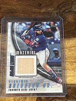 Baseball card with image of Vladimir Guerrero Jr. holding a bat, includes inset wooden piece from game-used bat, card in protective sleeve.