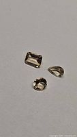 Photo of three natural champagne morganite gemstones showing different cuts and champagne tint color.