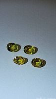 Four oval faceted yellow sapphires on white background, showing clear brilliance and color.