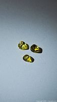 Three individual pear cut lemon yellow sapphires displayed on a plain white background with natural light showing their bright clarity and color.