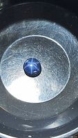 Natural round blue cabochon sapphire with 6-ray star asterism effect visible under light.