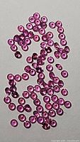 Multiple loose untreated hot pink sapphires with excellent clarity and cut scattered on a white background.
