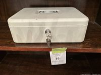 Large white metal lockbox with key on shelf