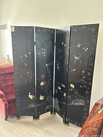 Full view of the four-panel decorative black folding screen with painted floral and bird motifs.