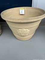 Side view of the large terra-cotta plant pot showing floral emblem and wide rim.