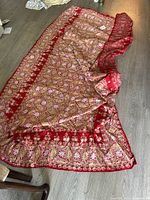 Full view of the red embroidered tablecloth spread out on floor showing overall size and border embroidery.