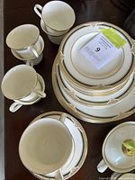 Various dinnerware pieces including plates, cups and saucers arranged on a table showing full set.