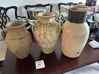 Photo showing three vintage stoneware vases on table including Turkish terracotta vase, rattan wrapped earthenware vessel, and large two-toned ceramic vase.