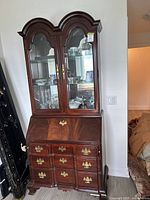 Front view of the complete wood china cabinet hutch with closed glass doors and visible drawers and drop-front desk panel.