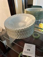 Stacked set of white soup bowls with scalloped edges and gold trim around rims.