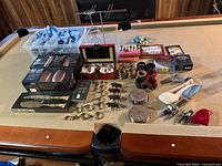 Full view of the assorted barware and party items arranged on a table showing various metal coasters, plastic bins, glasses, and boxes of copper mugs.