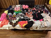 Top-down view on a bed of assorted bathing suits and cover ups in multiple colors and patterns laid out to show variety.