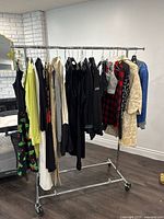 Overall view of assorted ladies clothing on rack showing dresses, tops, and outerwear in different colors.