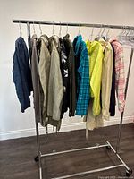 Wide view of 9 assorted ladies jackets hanging on rack showing variety of colors and materials.
