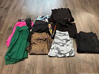 Assortment of ladies pants, shorts, and skirts laid out on floor, showing varied colors and prints.