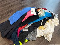 Photo showing an assortment of ladies medium size tank tops and tees in various colors, some with tags attached. Different brands like Zara, Old Navy, and Gap visible on tags.