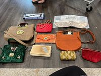 Nine assorted purses of various styles and colors displayed on floor showing materials and detailing