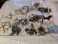 Photo showing wide assortment of costume jewelry pieces including bracelets, rings, and necklaces packaged in plastic and on cards.