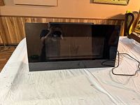 Front view of the black glass-fronted electric fireplace panel showing its sleek rectangular design.