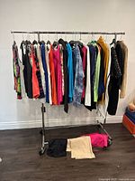 Full view of ladies clothing on metal rack with hangers and bottoms folded under rack
