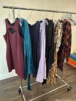 Photo of seven assorted ladies dresses hanging on rack showing full length views and colors.