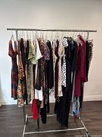 Photo of a rack featuring approx 15 assorted ladies dresses in sizes XS and Small with various colors, prints, and patterns
