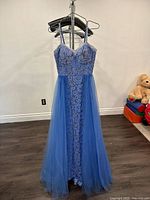 Front view of the full blue gown showing sheer tulle overlay and floral embroidered fabric underneath