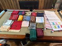 Full view of assorted linen napkin sets and double-sided Easter table runner displayed on pool table.