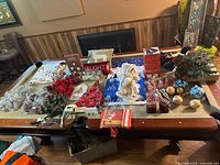 Wide view of the Christmas decor items arranged on a table, showing various ornaments, floral decor, angel figurines, signs, and lights.