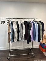 Full view of assorted men's shirts hanging on a clothing rack against a white wall.